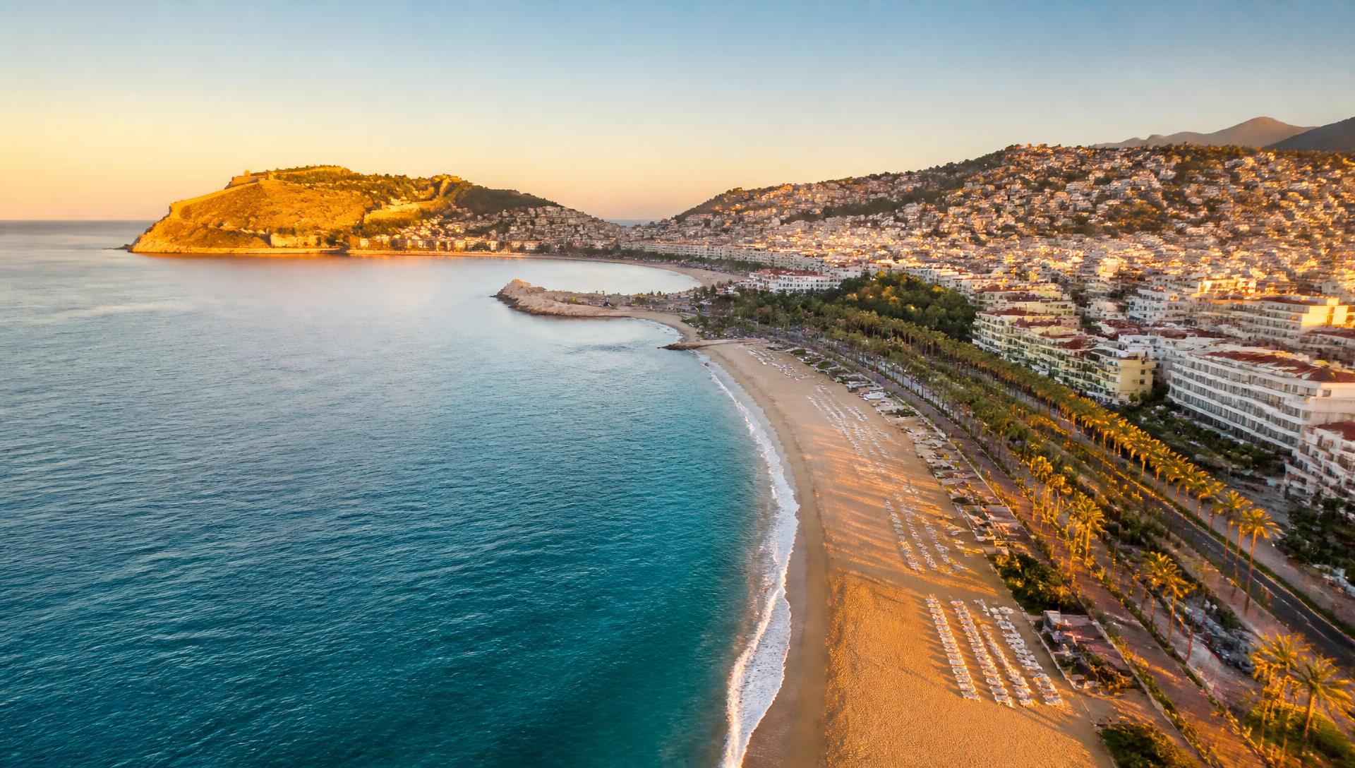 Küste von Alanya im Abendlicht mit Strand, Palmen und Burgberg
